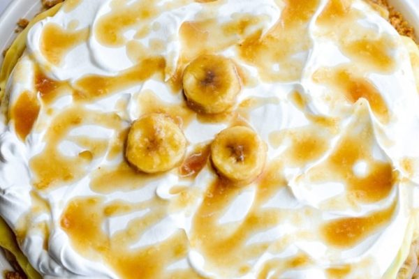 A banana pie with whipped cream and banana slices.