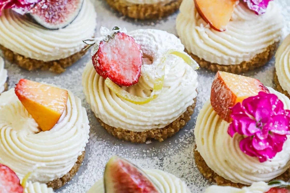 A festive collection of cupcakes adorned with vibrant fruits and delicate flowers.