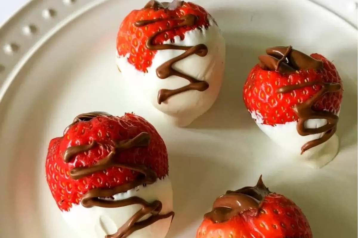 Nutella-covered strawberries on a plate.
