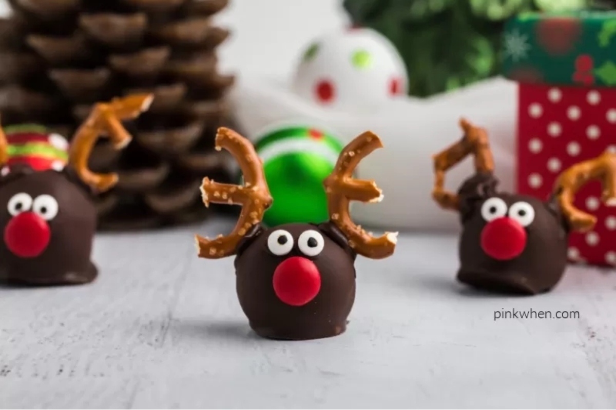 Oreo reindeer with red noses in front of Christmas decorations.