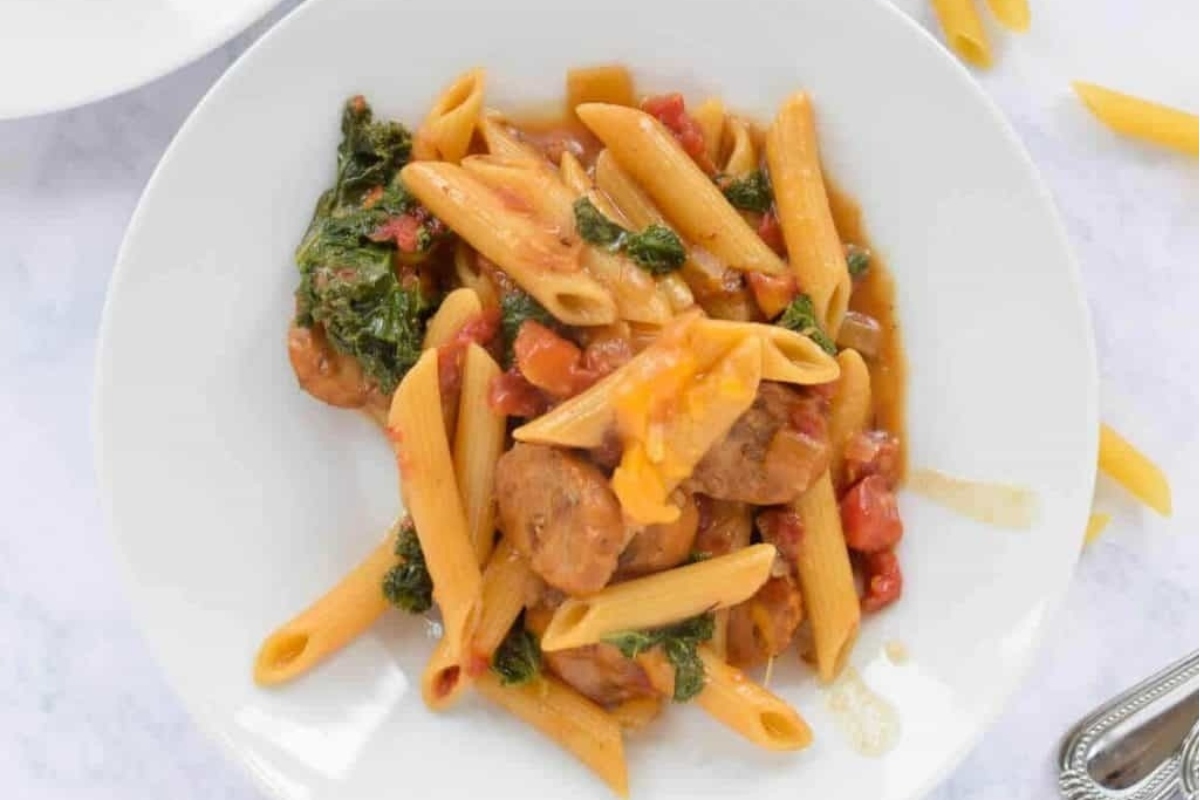Parents Love: Penne with sausage and spinach on a white plate is a delicious and hearty meal that parents will adore. 
Kid Friendly Recipes: Penne with sausage and spinach on a white plate is