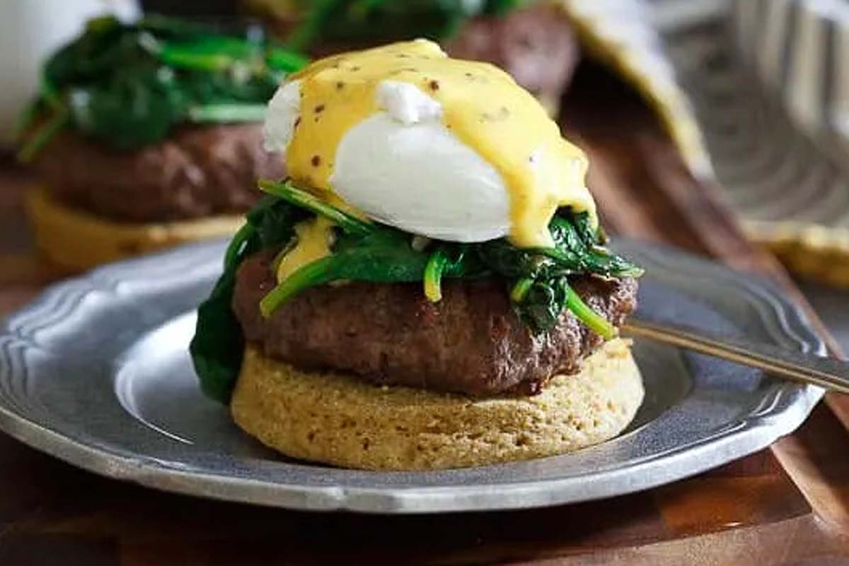Beef benedict topped with spinach and eggs.