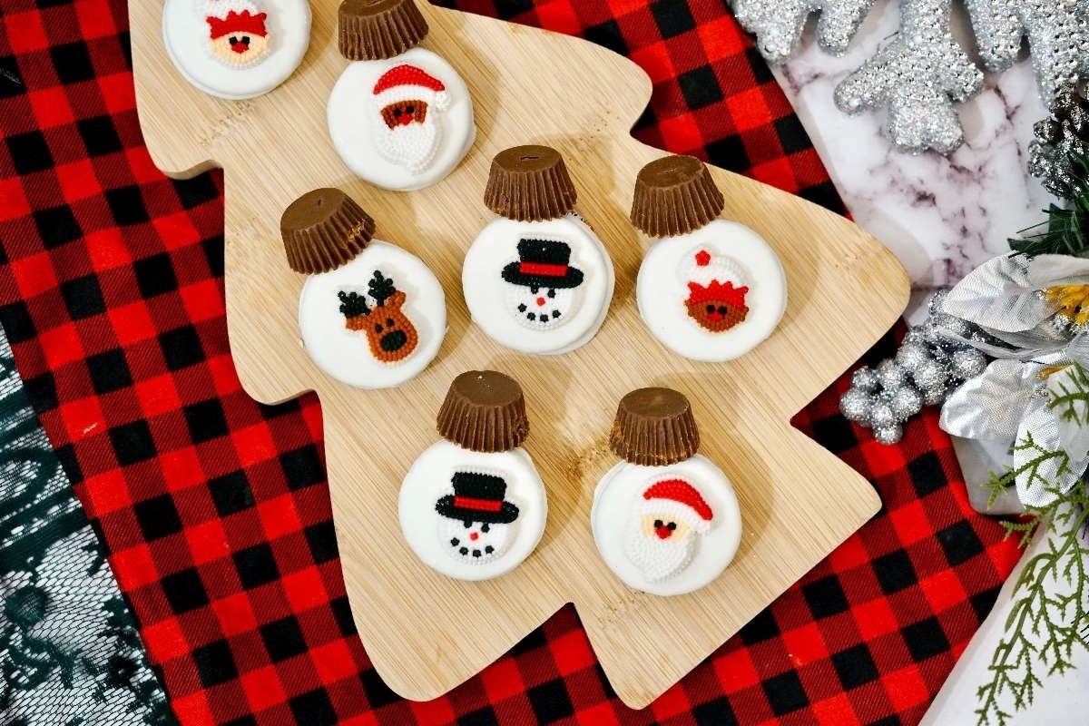 Christmas snowman cookies made with Oreos arranged on a wooden cutting board.