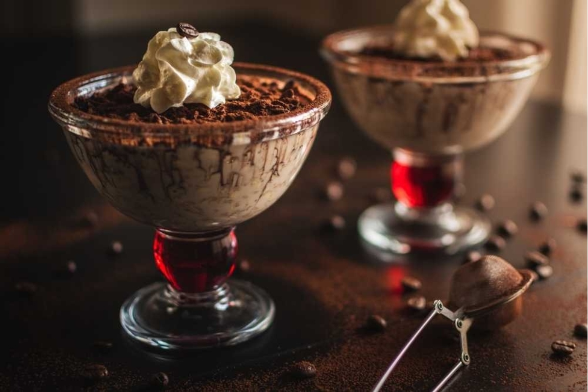 Two glasses of Italian chocolate pudding with whipped cream on top.