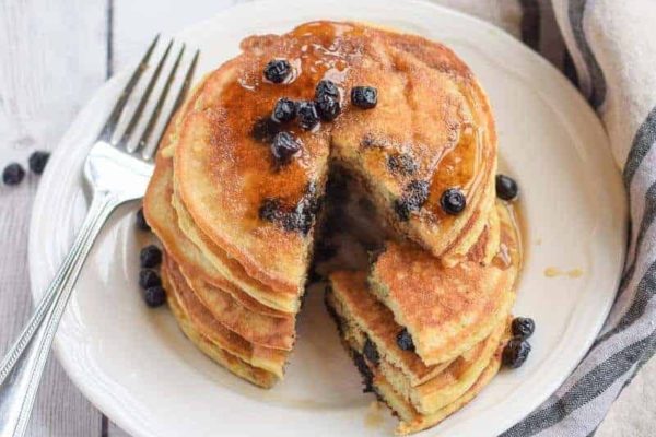 Blueberry pancakes on a white plate with a fork.