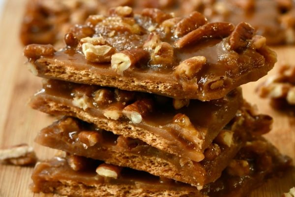 A stack of caramel pecan fudge on a cutting board.