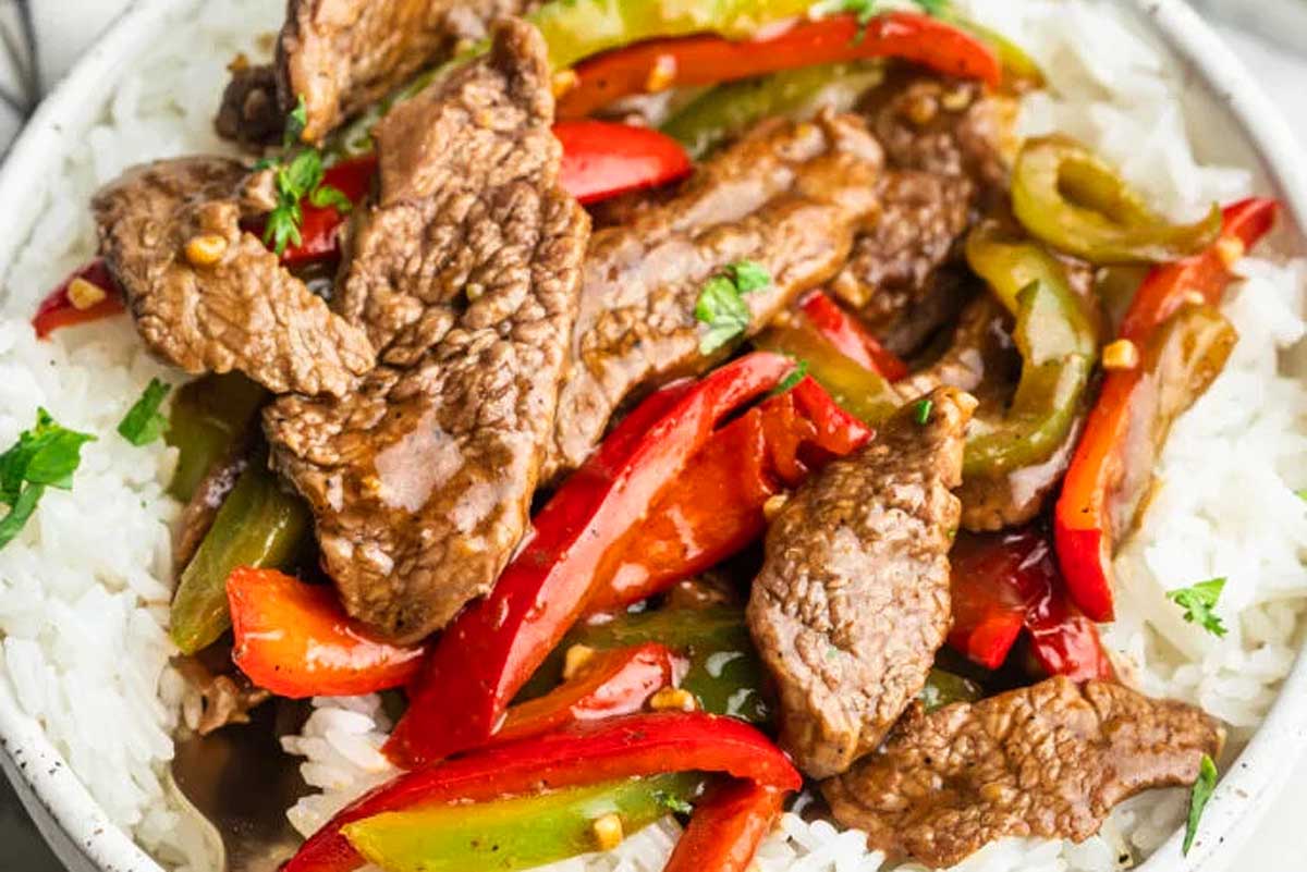 A bowl of beef stir fry with peppers and rice.