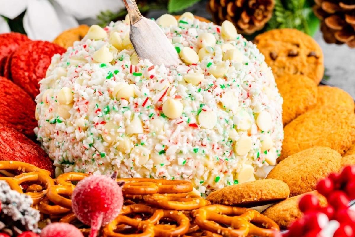 A festive Christmas cheese ball adorned with cookies and pretzels, perfect for holiday gatherings.