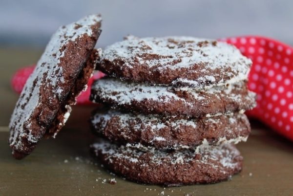 A stack of chocolate cookies with powdered sugar on top.