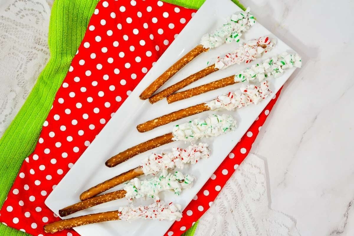 Christmas pretzels drizzled with white chocolate on a white plate with red and green polka dots.