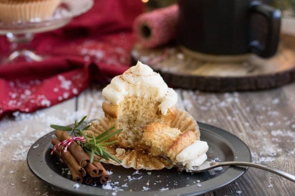 A Christmas cupcake with cinnamon and sprigs on a plate.