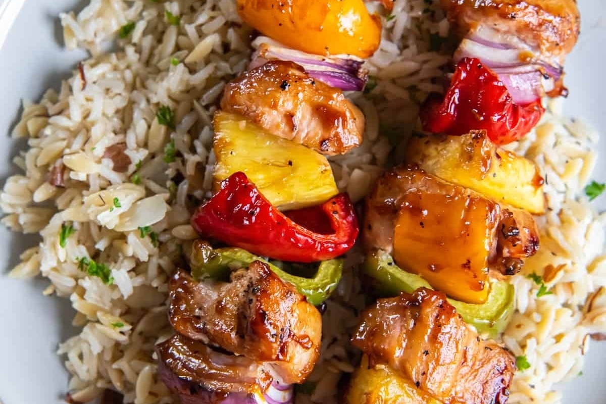 Inspired by a Hawaiian Luau, these chicken skewers are served on a plate with rice.