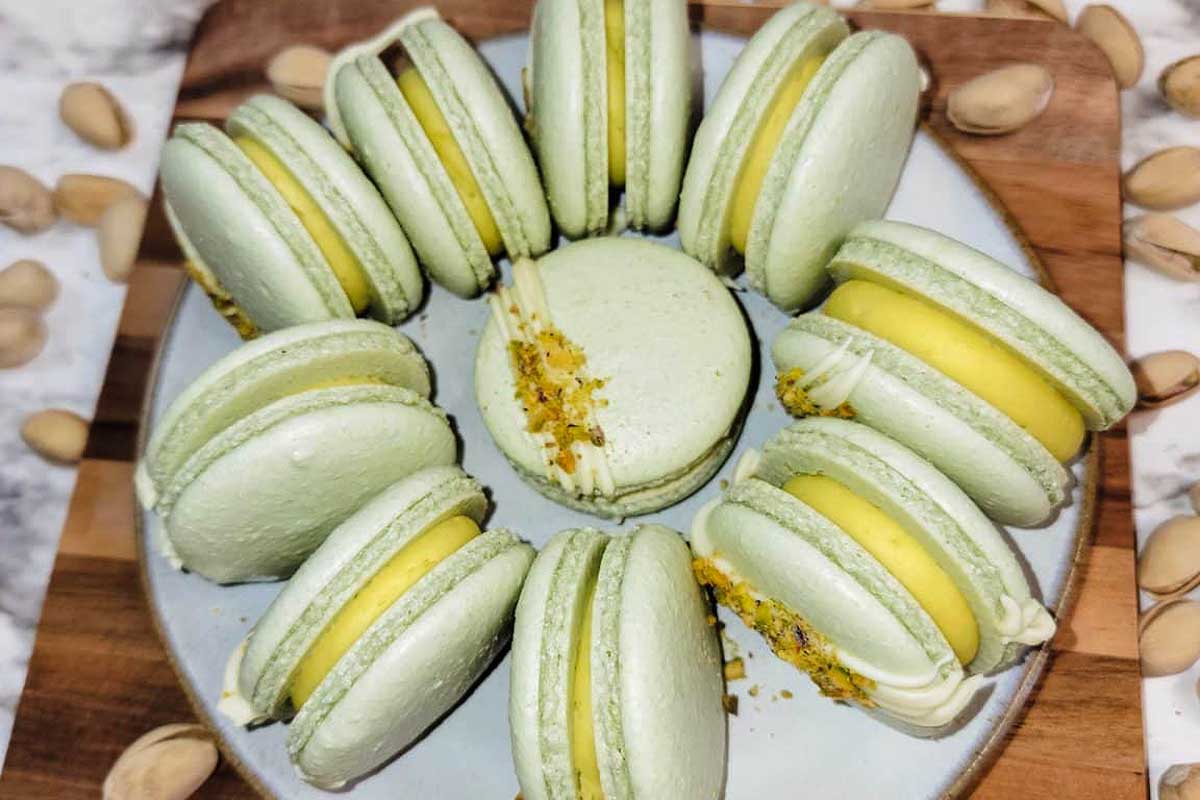 Green macarons with pistachios on a plate. These delectable treats are made using pistachio recipes, resulting in a unique and irresistible flavor.