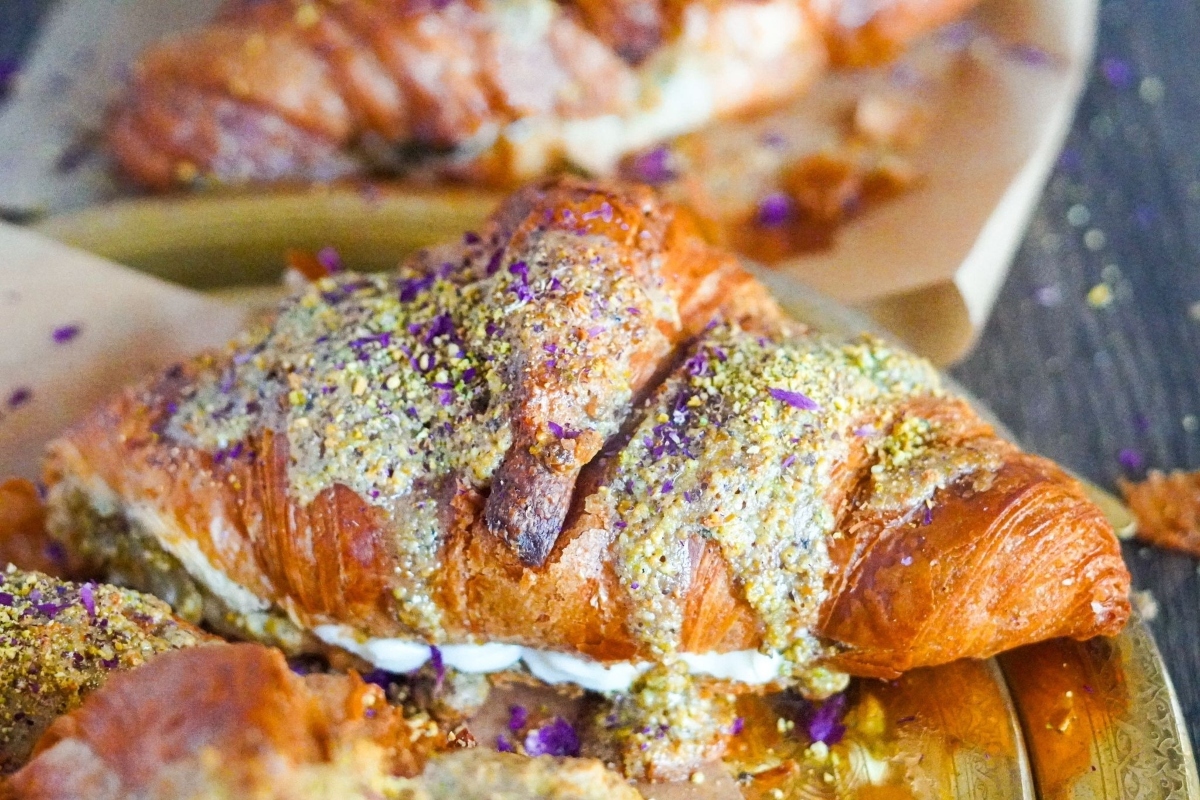 Two croissants topped with pistachio cream are sitting on a plate.