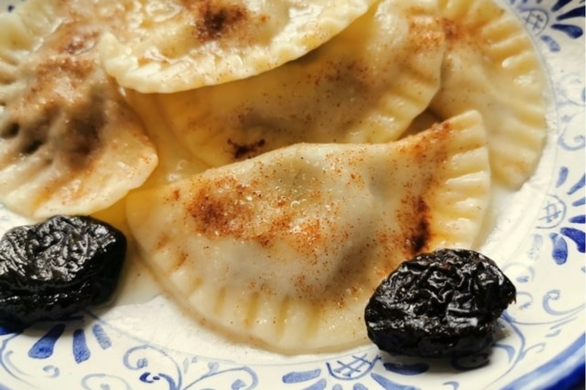 An Italian dessert plate with dumplings and raisins on it.