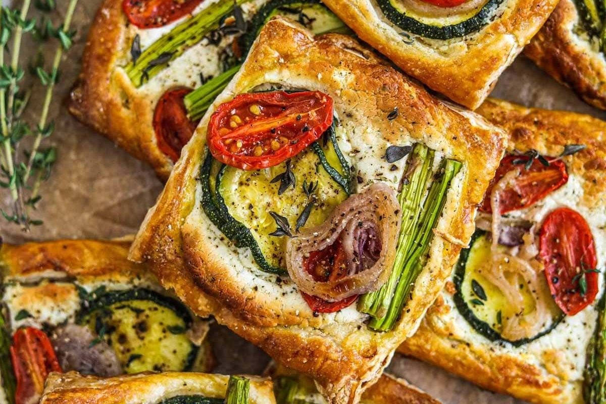 Festive Christmas party appetizers featuring vegetable tarts adorned with thyme and sprigs.