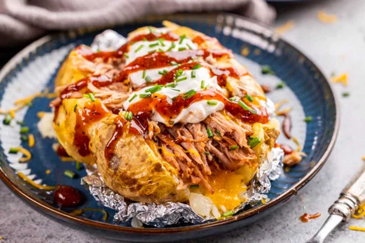 A baked potato topped with pulled pork and sour cream.