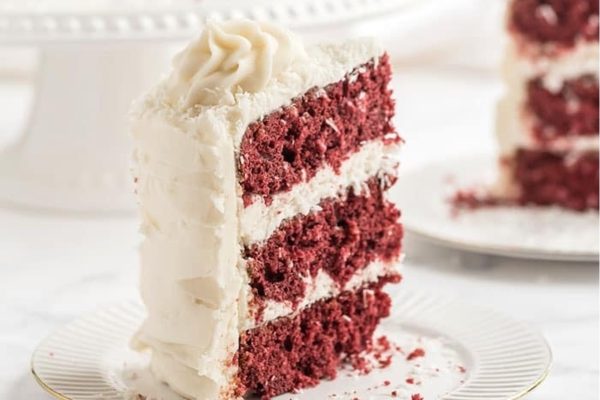A decadent slice of Red Velvet cake, with its rich crimson hue and moist crumb, beautifully presented on a plate.