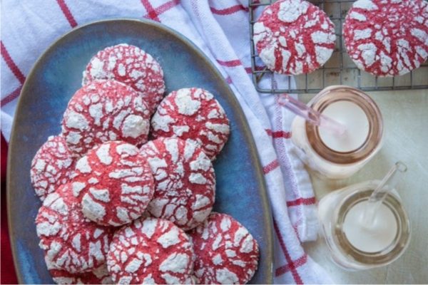 Red velvet crinkle cookies on a plate next to a glass of milk.