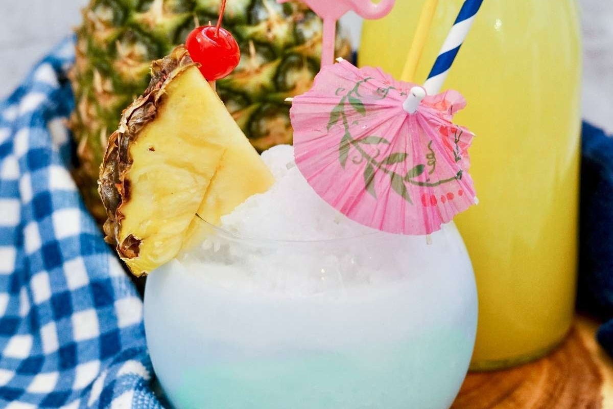 A Hawaiian-inspired drink with a pineapple on top, featuring vibrant blue and pink colors. Ideal for luau gatherings.