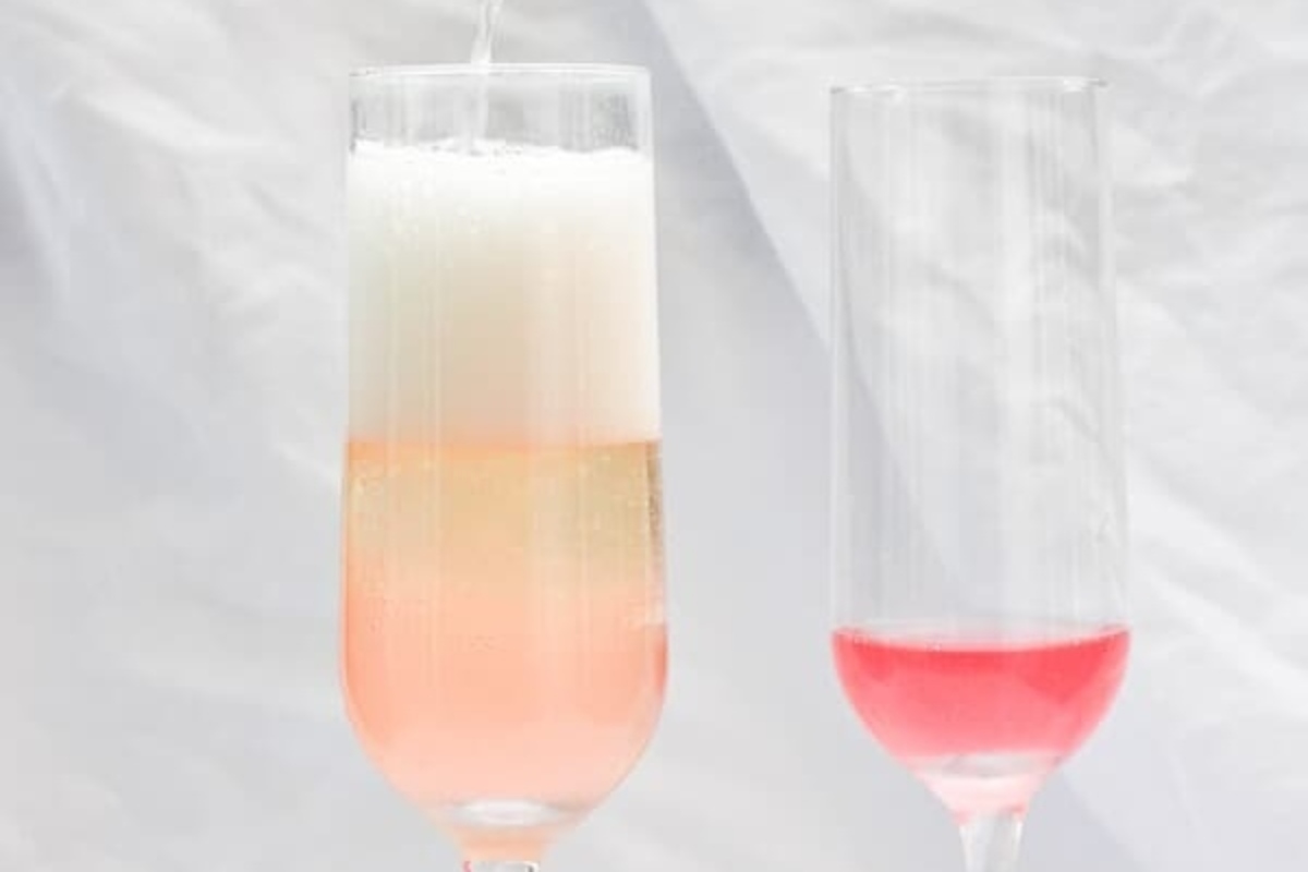 Two glasses of champagne cocktails with pink liquid in them.