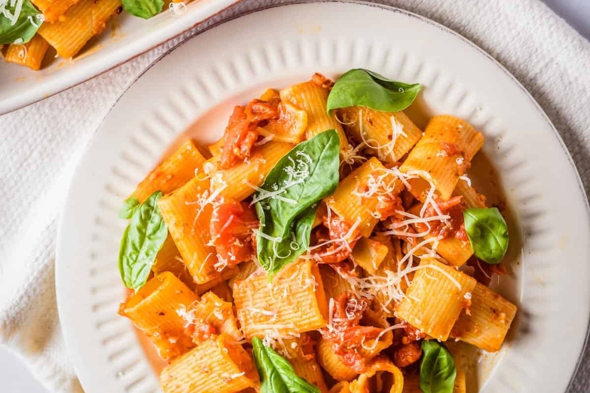 A mouthwatering Italian main dish of pasta topped with fresh tomatoes and fragrant basil, presented beautifully on a plate.