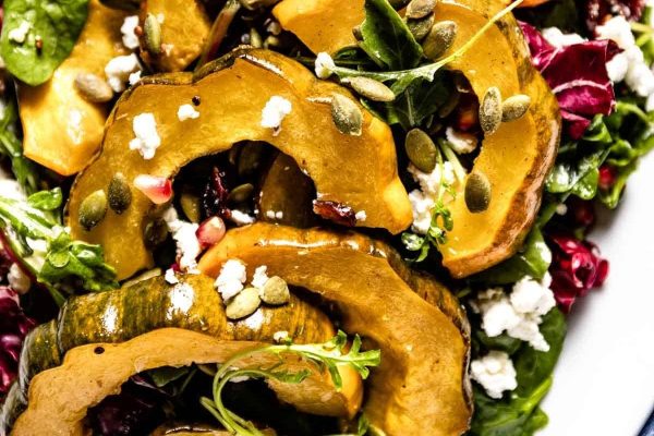 A plate of roasted squash salad with feta and pomegranate seeds.
