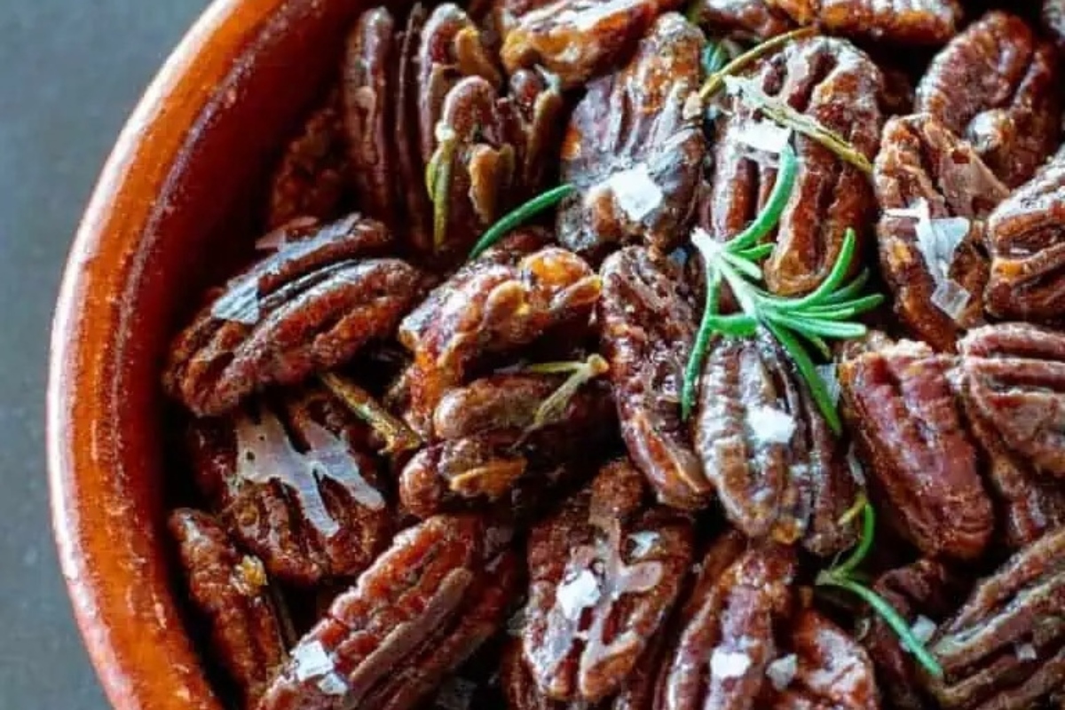 Pecans in a bowl with rosemary sprigs, perfect for Pecan Recipes.