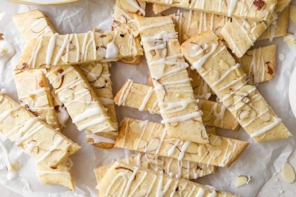 Sliced almond cookies with a drizzle of icing.