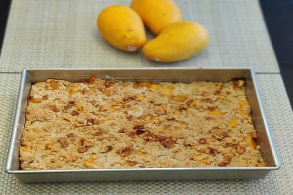 Mango crumble in a metal pan with mangoes.