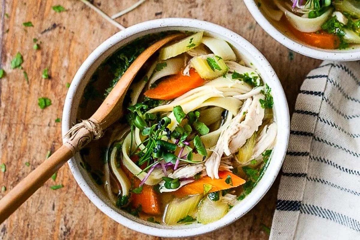 A Slow Cooker soup with chicken, noodles, carrots and parsley.