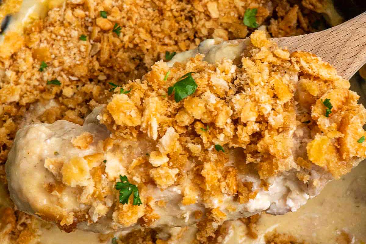 Chicken in a casserole dish with a spoonful of crumbs.