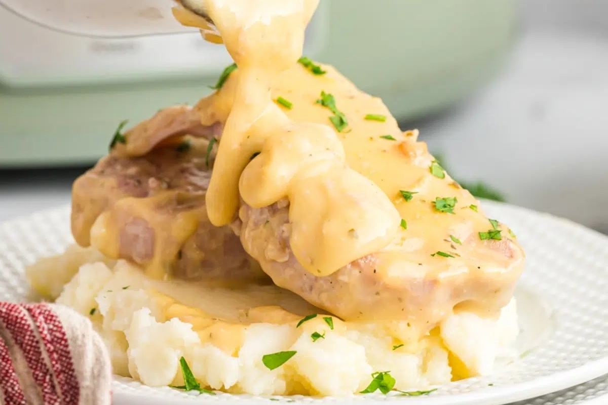 Instant pot pork chops with gravy being poured over mashed potatoes.