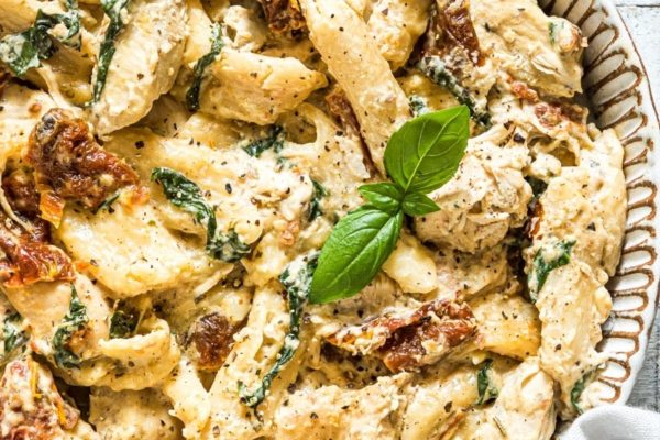 A bowl of pasta with chicken and spinach.