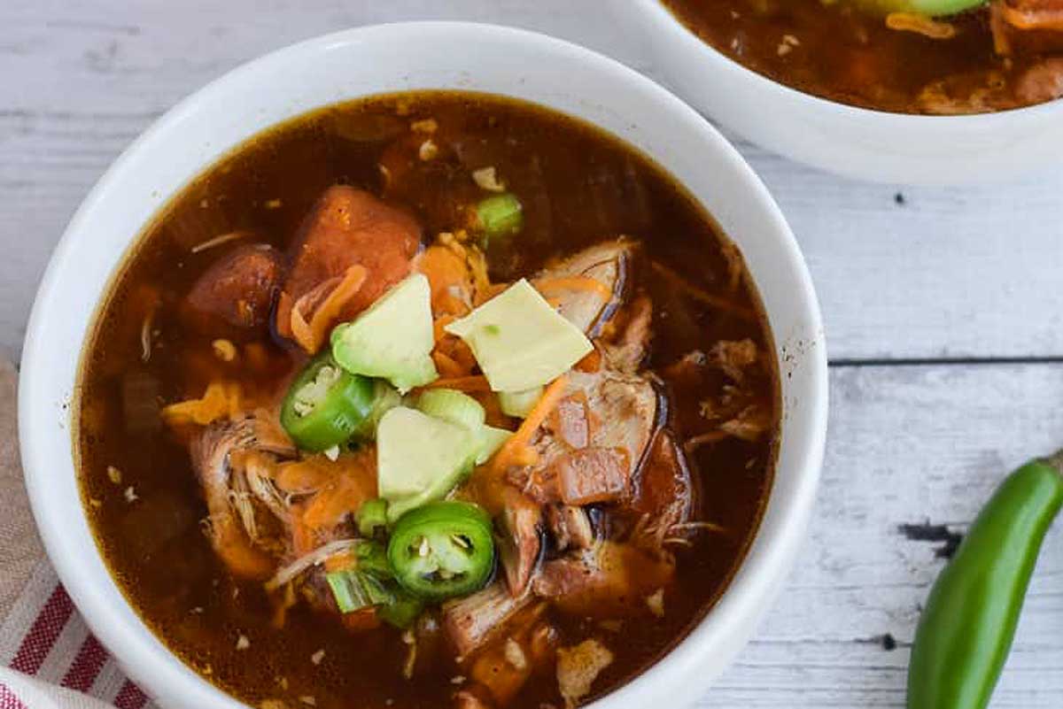 Slow Cooker Mexican chicken soup in a white bowl on a wooden table.