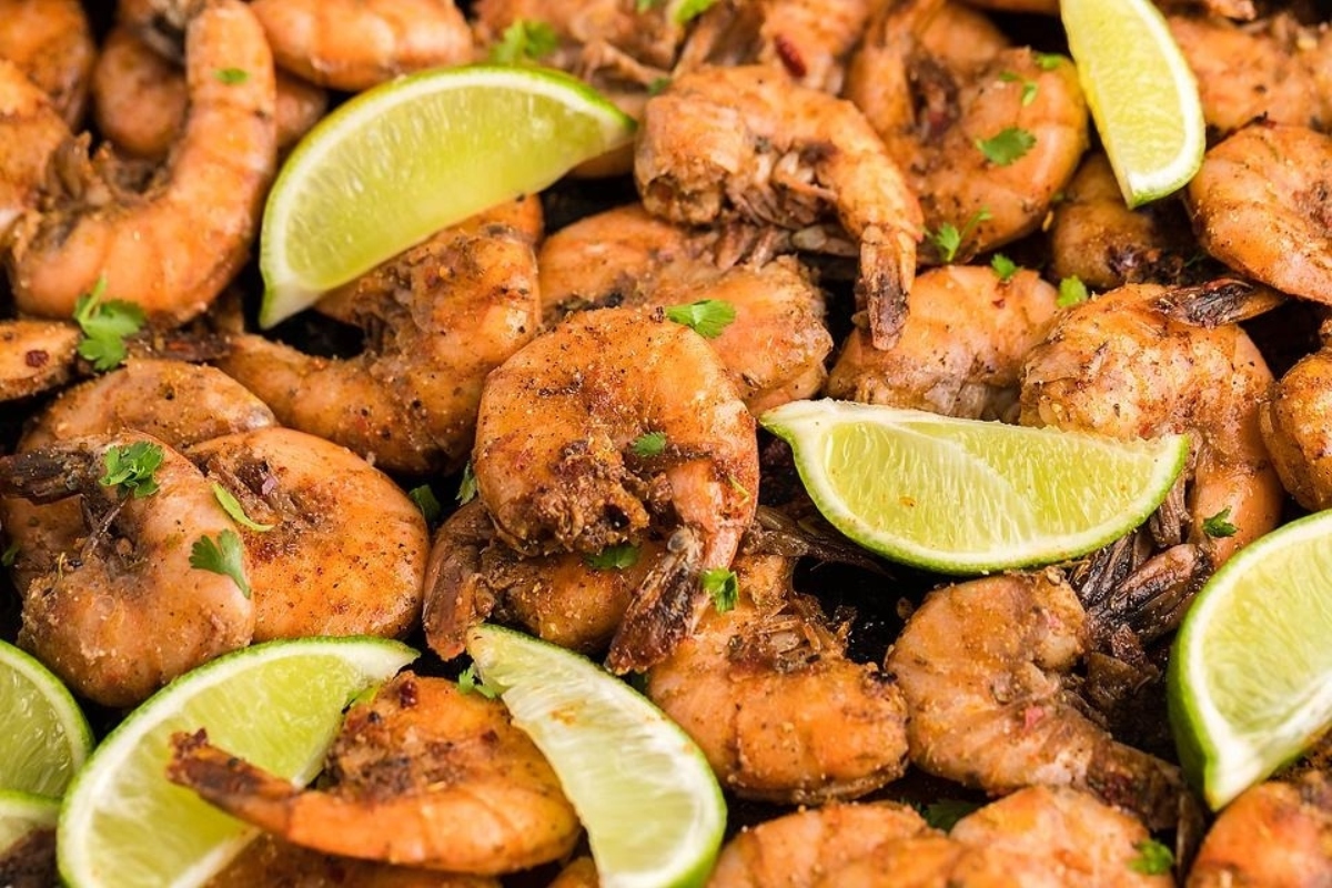 Grilled shrimp with lime wedges on a plate.