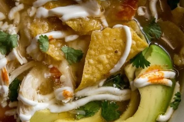 A classic bowl of chicken enchilada soup with avocado and sour cream, reminiscent of 1950's comfort food.