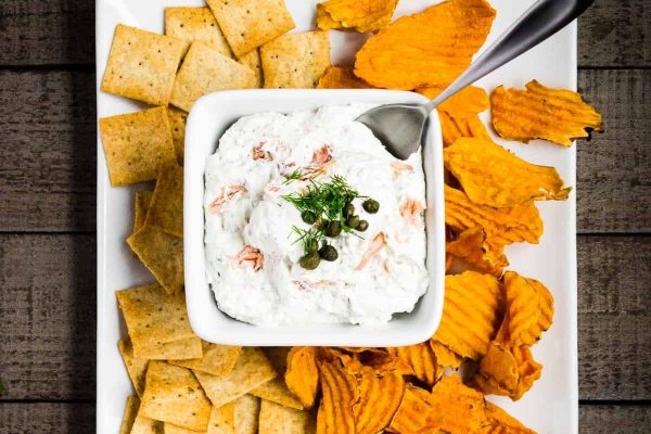 Salmon dip with crackers on a white plate.