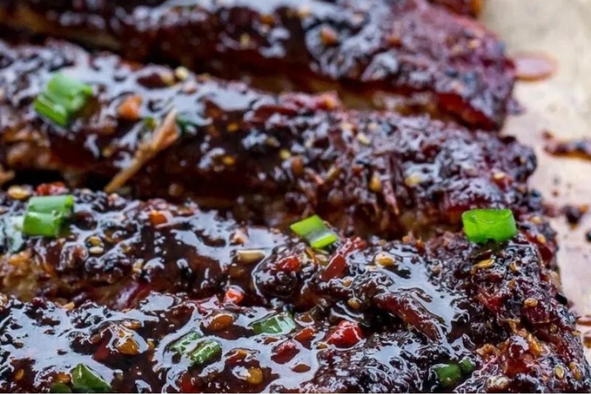 Ribs with sauce and green onions on a cutting board in delicious recipes.