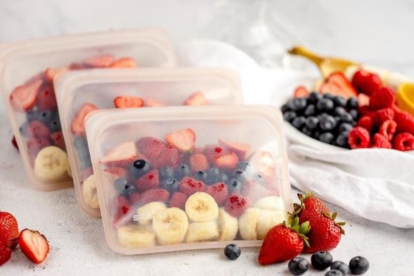 Four plastic containers filled with fruit and berries.