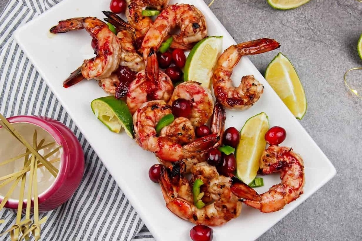 Grilled shrimp with cranberries, perfect for Christmas party appetizers, presented on a white plate.