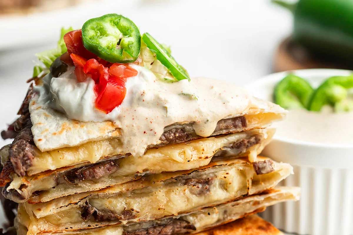 A stack of quesadillas with cheese and sauce.