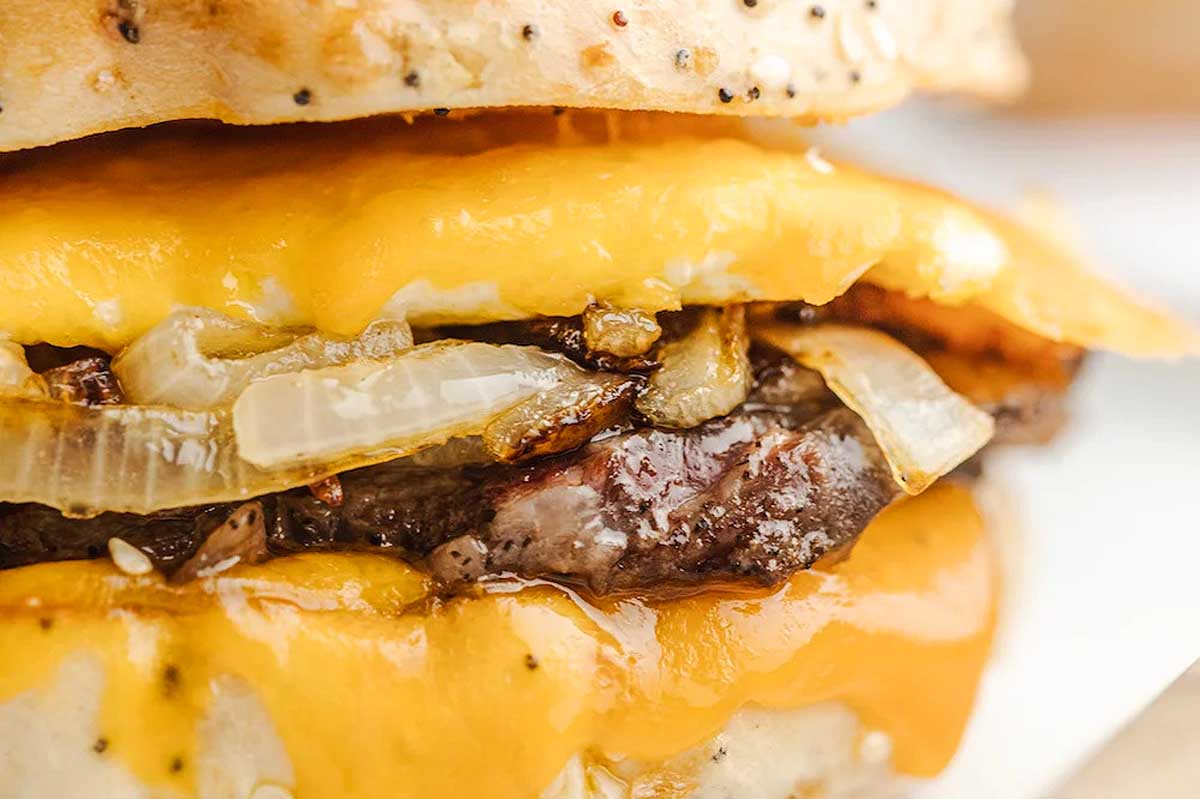 A close up of a burger with onions and cheese.