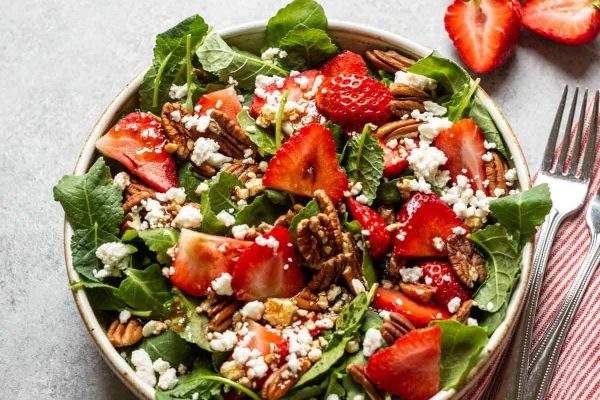Colorful strawberry spinach salad with feta and pecans.