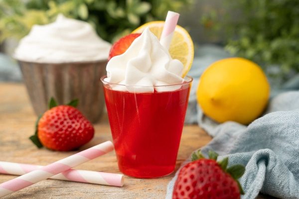 Refreshing strawberry lemonade served in a cup topped with fluffy whipped cream and fresh strawberries.
