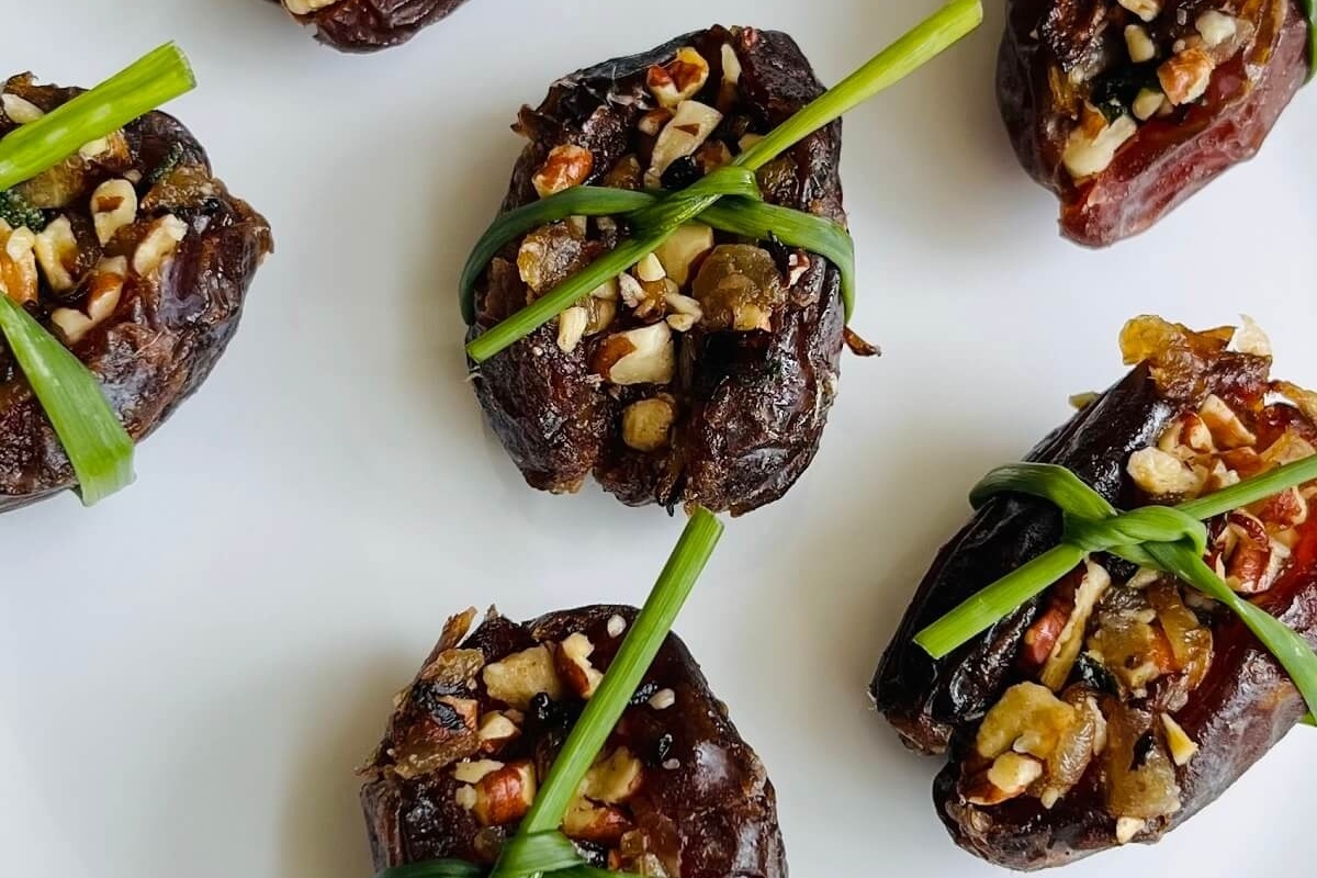 Festive Christmas party appetizers featuring dates with nuts and greens arranged on a plate.