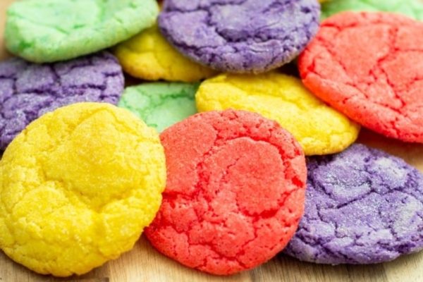 Colorful crinkle cookies on a wooden cutting board. These eye-catching treats are made using simple jello recipes, resulting in vibrant and delicious cookies that are sure to impress.