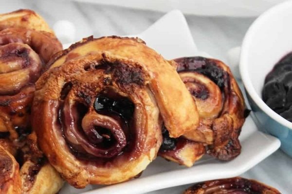 A plate of blueberry cinnamon rolls with a blueberry sauce.