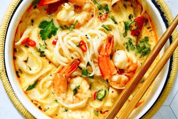 An Asian bowl of shrimp noodle soup with chopsticks.