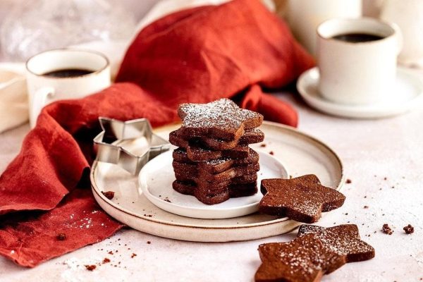 A plate of chocolate cookies on a plate with a cup of coffee. The perfect Christmas dessert.